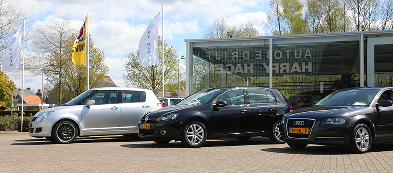 De gevel van Autobedrijf Harry Hagen met occasions op het terrein