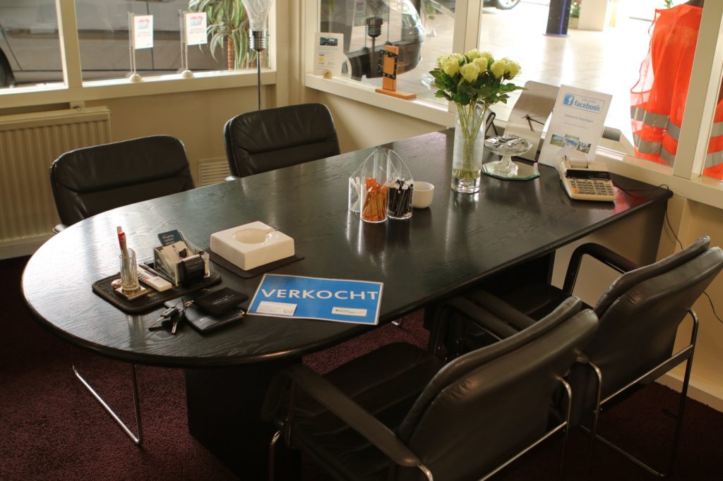 De verkooptafel in de showroom met een bos rozen en het bordje Verkocht